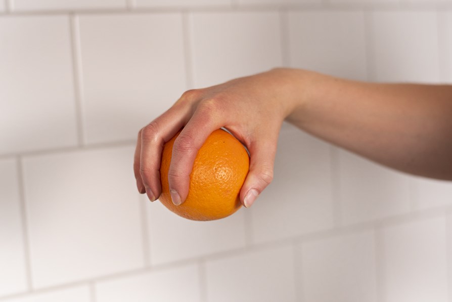 Hånd, der holder en appelsin.